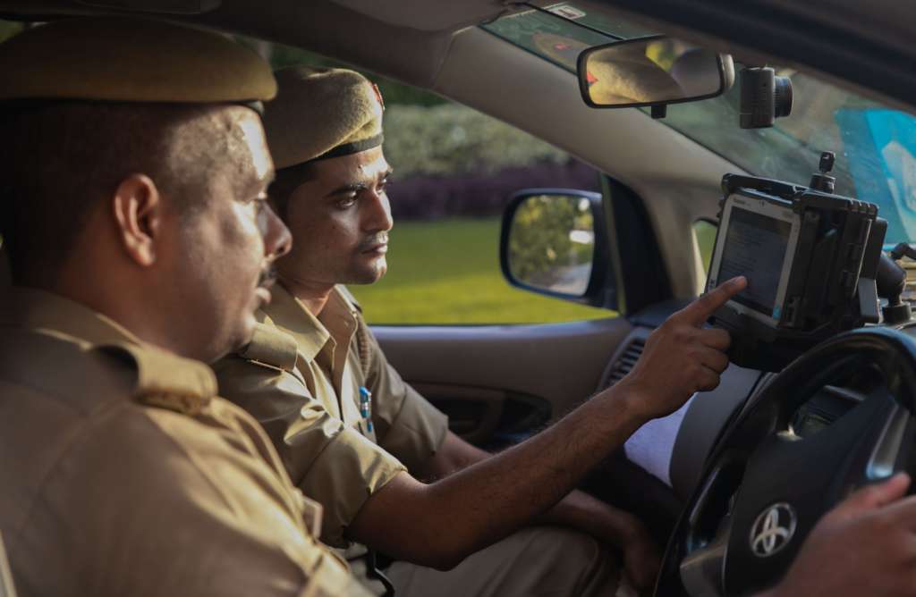 A photo of law enforcement officers analyzing data on tablets during a strategy meeting, showcasing the role of technology in crime prevention