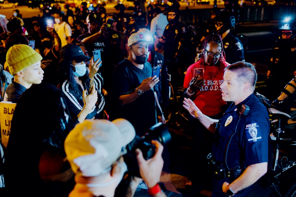 An image showing law enforcement officers engaging with community members about Crime Stoppers vs traditional reporting.